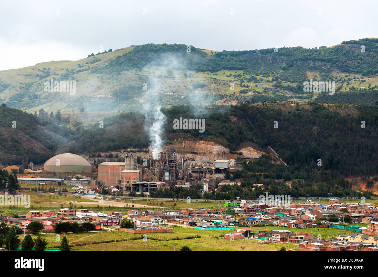 A factory producing pollution near a small town Stock Photo