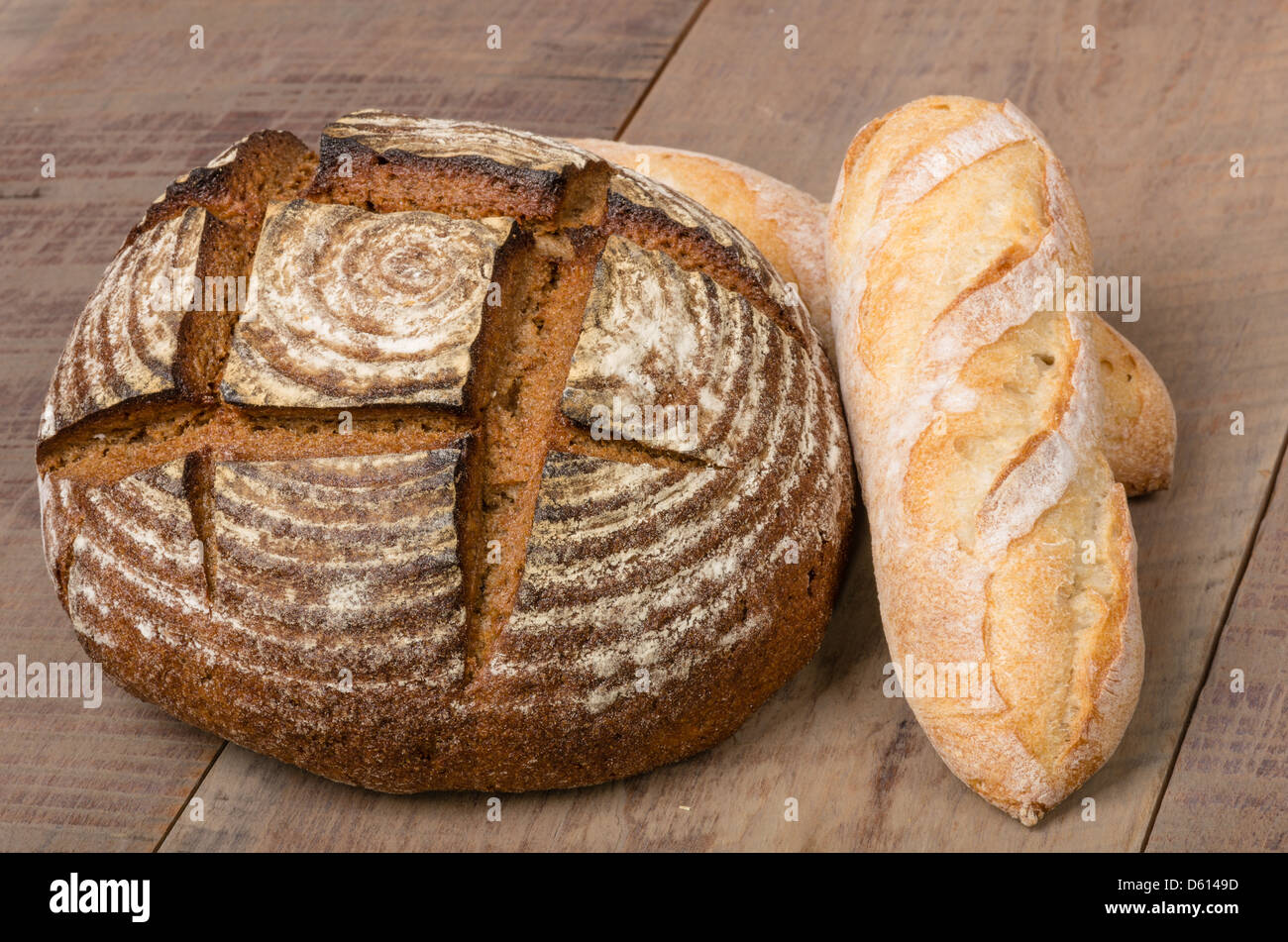 A loaf of fresh rye bread on a table with french baguette loaf Stock ...