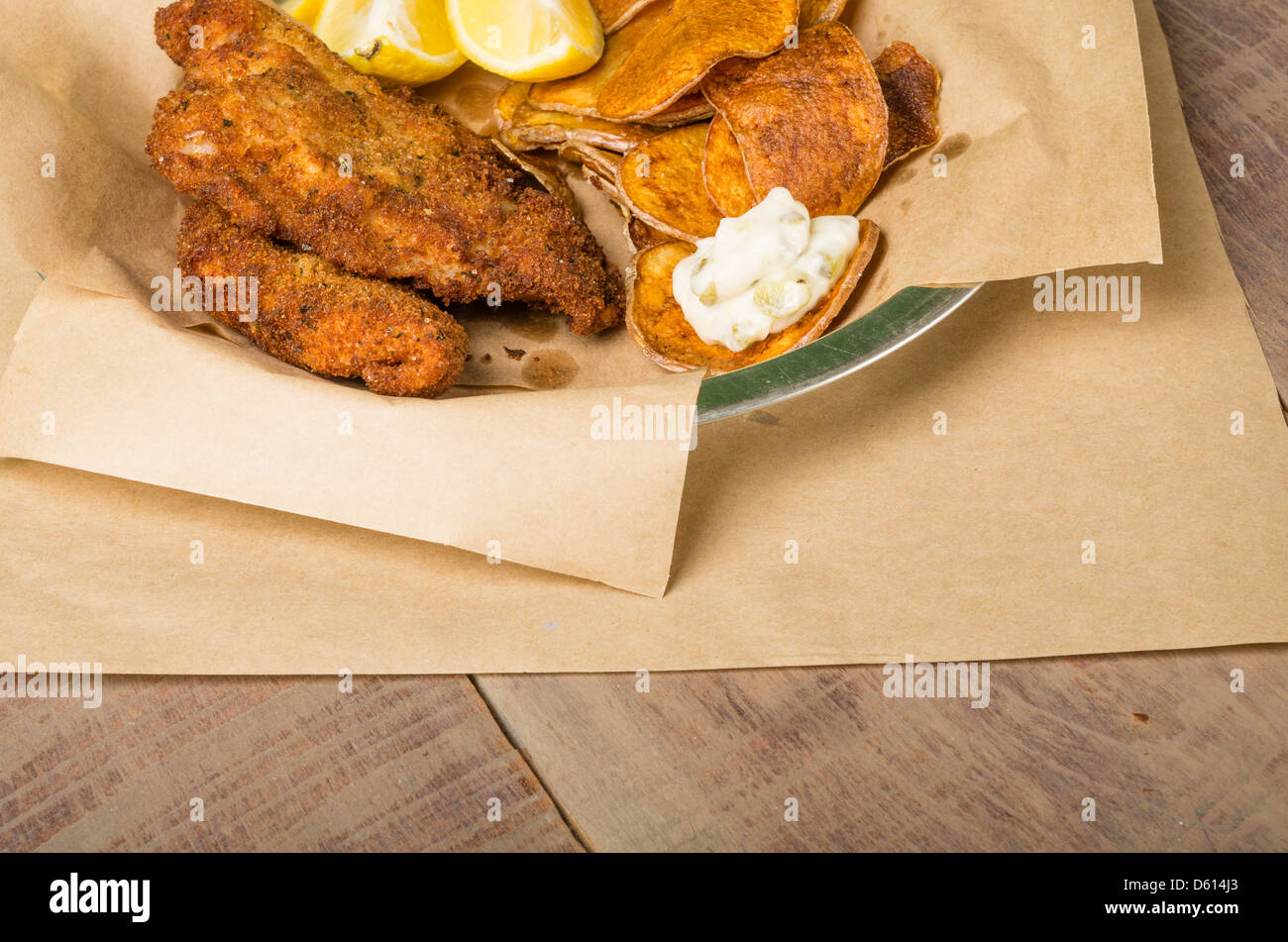 Fried fish and chips with lemon on a wooden table Stock Photo