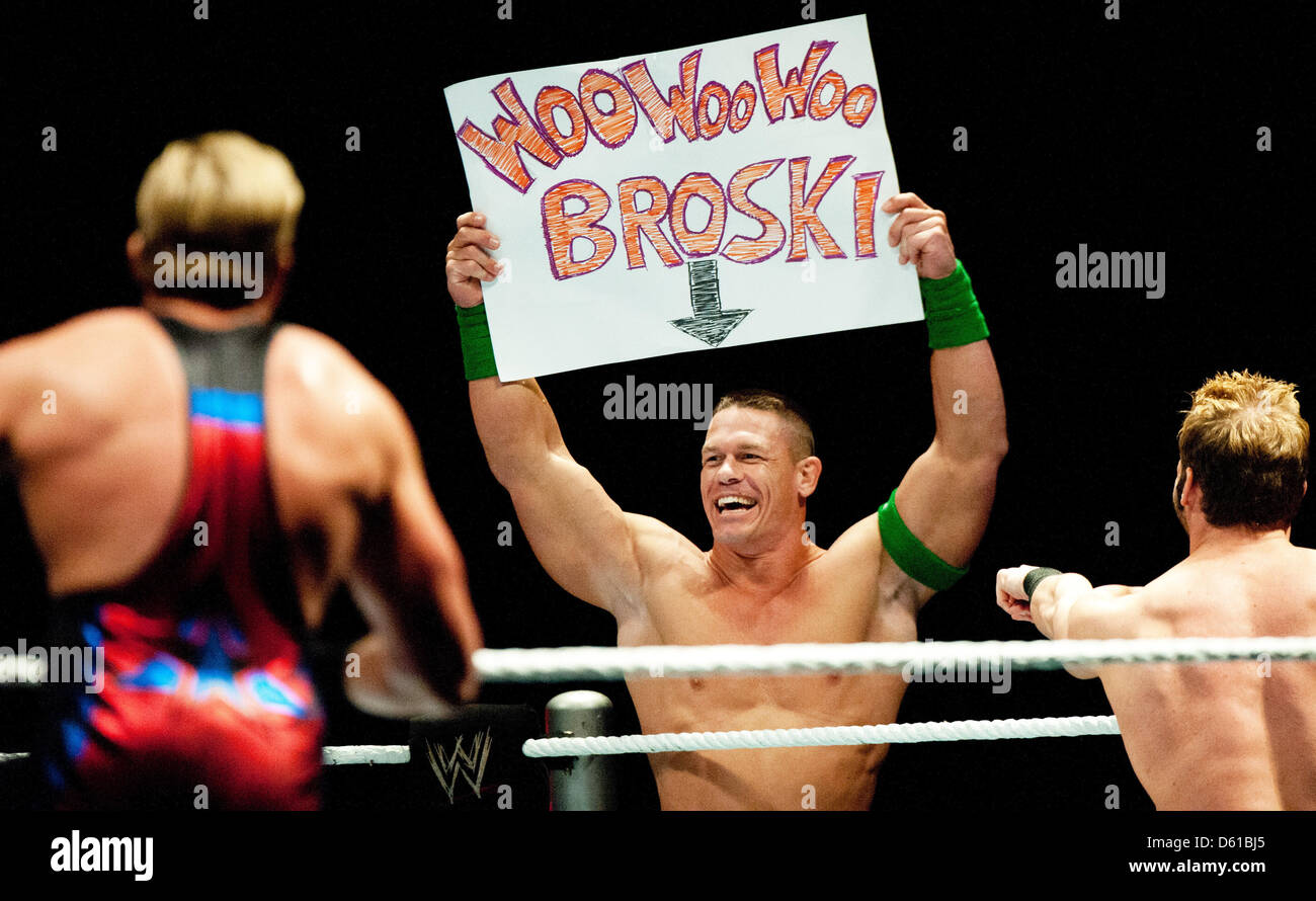 US-wrestler John Cena (C) holds up a poster which reads 'WooWooWoo Broski'  and cheers as he stands next to fellow US-wrestlers Jack Swagger (L) and Zack  Ryder during a fight at the
