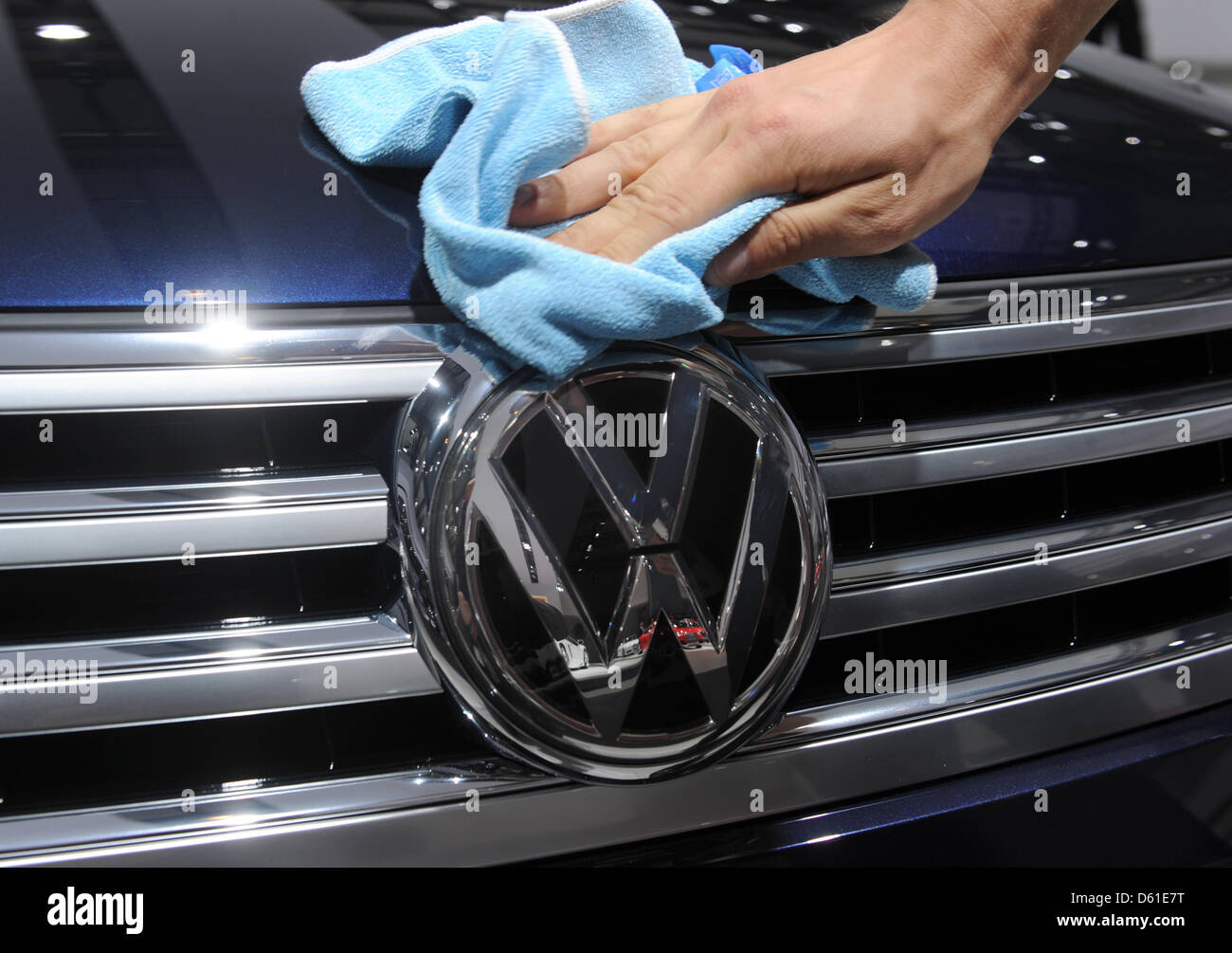 A man cleans a Volkswagen logo during the general meeting of car manufacturer  Volkswagen in Hamburg, Germany, 19 April 2012. Wife of Volkswagen Supervisory Board Ferdinand Piech, Ursula Piech, will be elected to the supervisory board during the meeting. Photo: MARCUS BRANDT Stock Photo