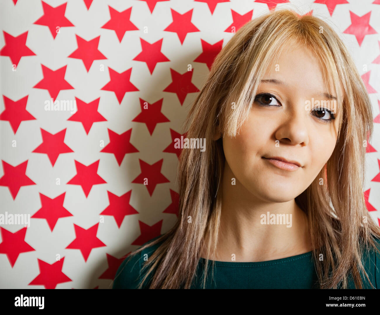 Close-up of beautiful young woman gainst red star shapes wallpaper Stock Photo