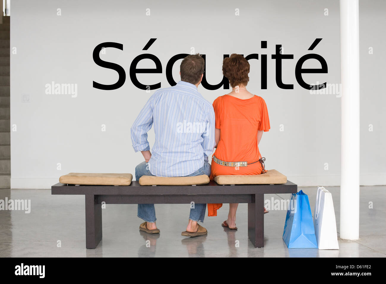 Rear view of couple reading French text 'sécurité' (security) contemplating bout security Stock Photo