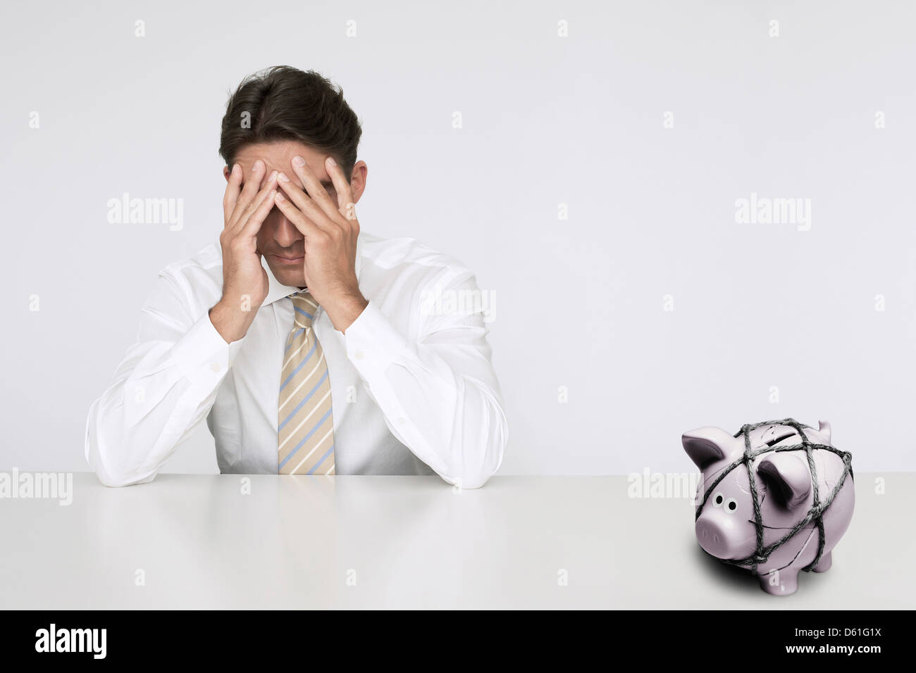 Worried businessman t table with trapped piggy bank representing ...
