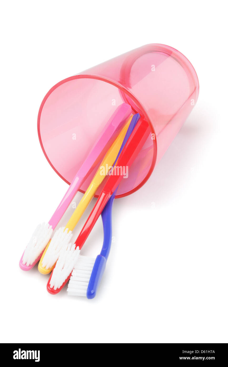 Colorful Toothbrushes In Plastic Cup Lying On White Background Stock Photo