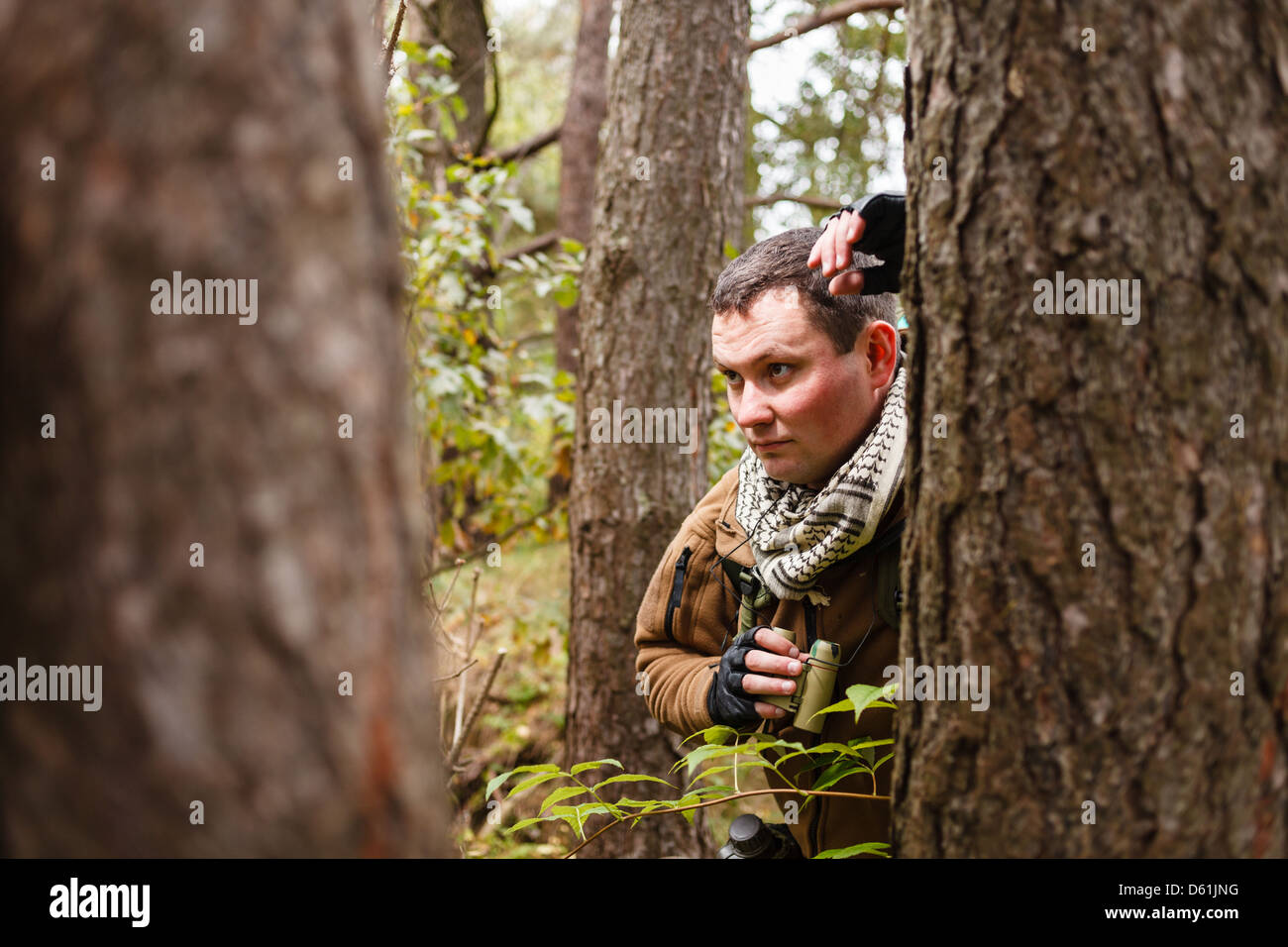Man with binoculars at a forest. Stock Photo