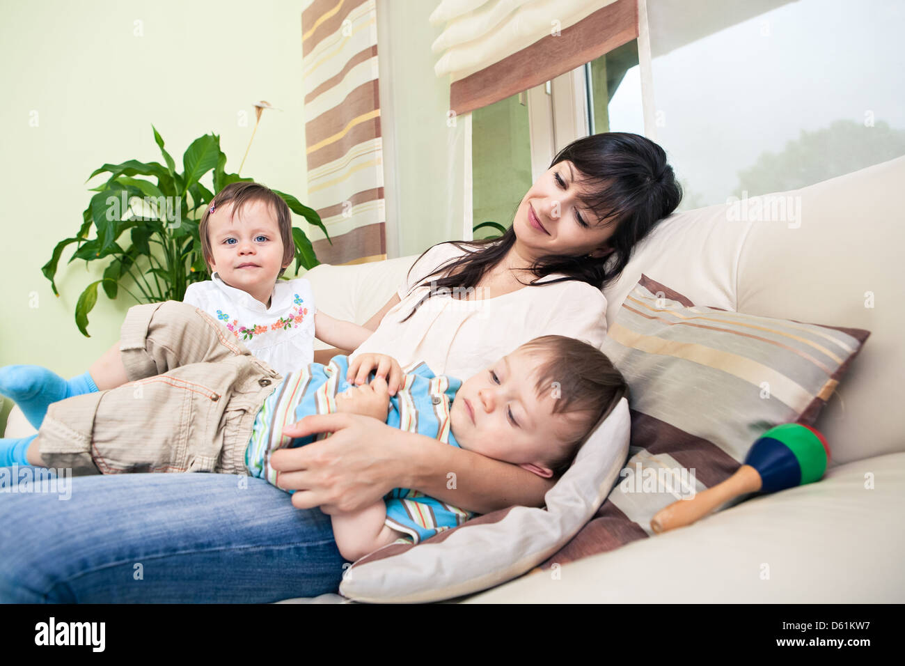 indoor portrait of a young woman with toddler twins in the living room Stock Photo