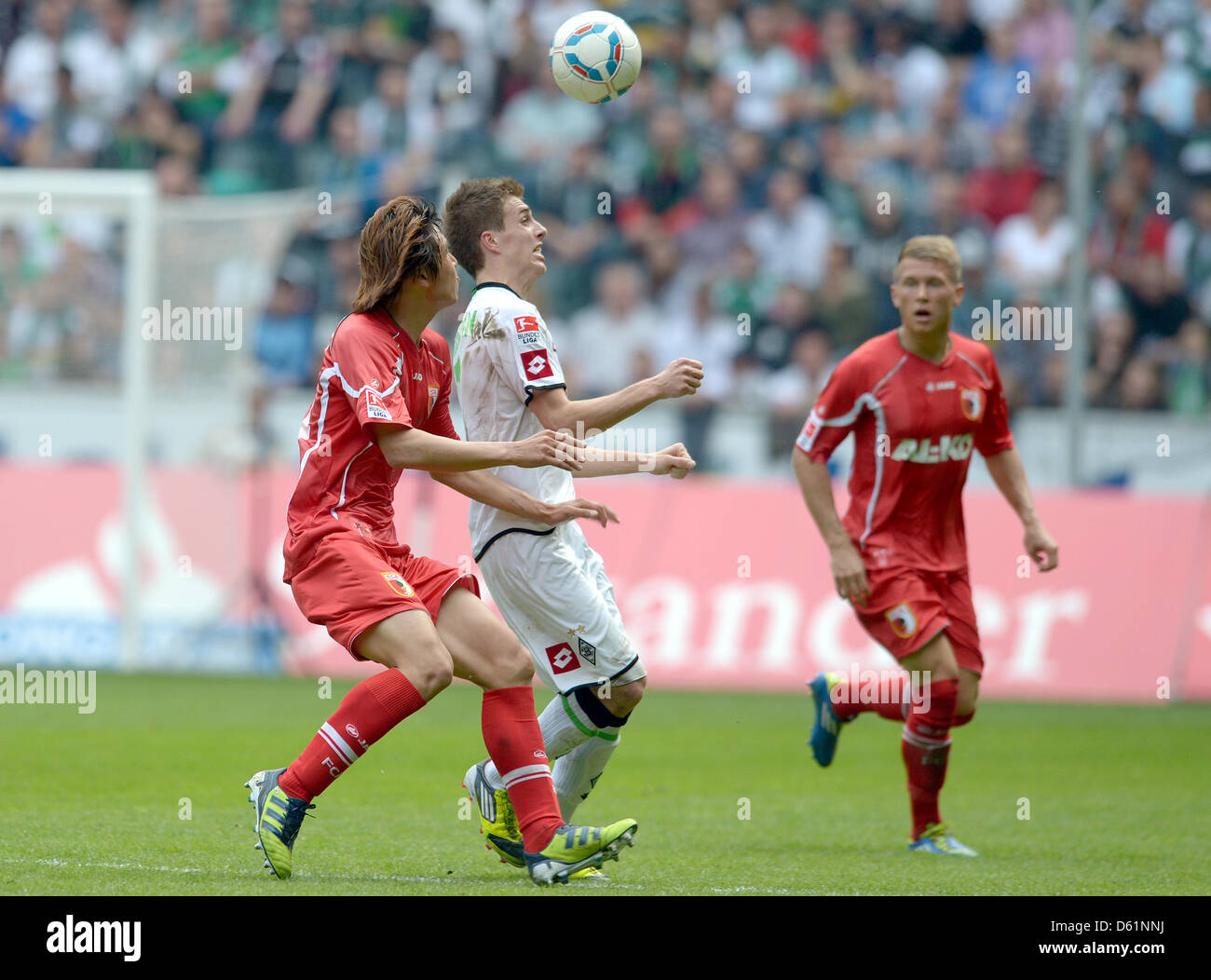 Gladbach's Patrick Herrmann (C) vies for the ball with Augsburg's Ja-Cheol Koo during the Bundesliga soccer match between Borussia Moenchengladbach and FC Augsburg and waves at Borussia-Park in Moenchengladbach, Germany, 28 April 2012. Photo: FEDERICO GAMBARINI  (ATTENTION: EMBARGO CONDITIONS! The DFL permits the further utilisation of the pictures in IPTV, mobile services and othe Stock Photo