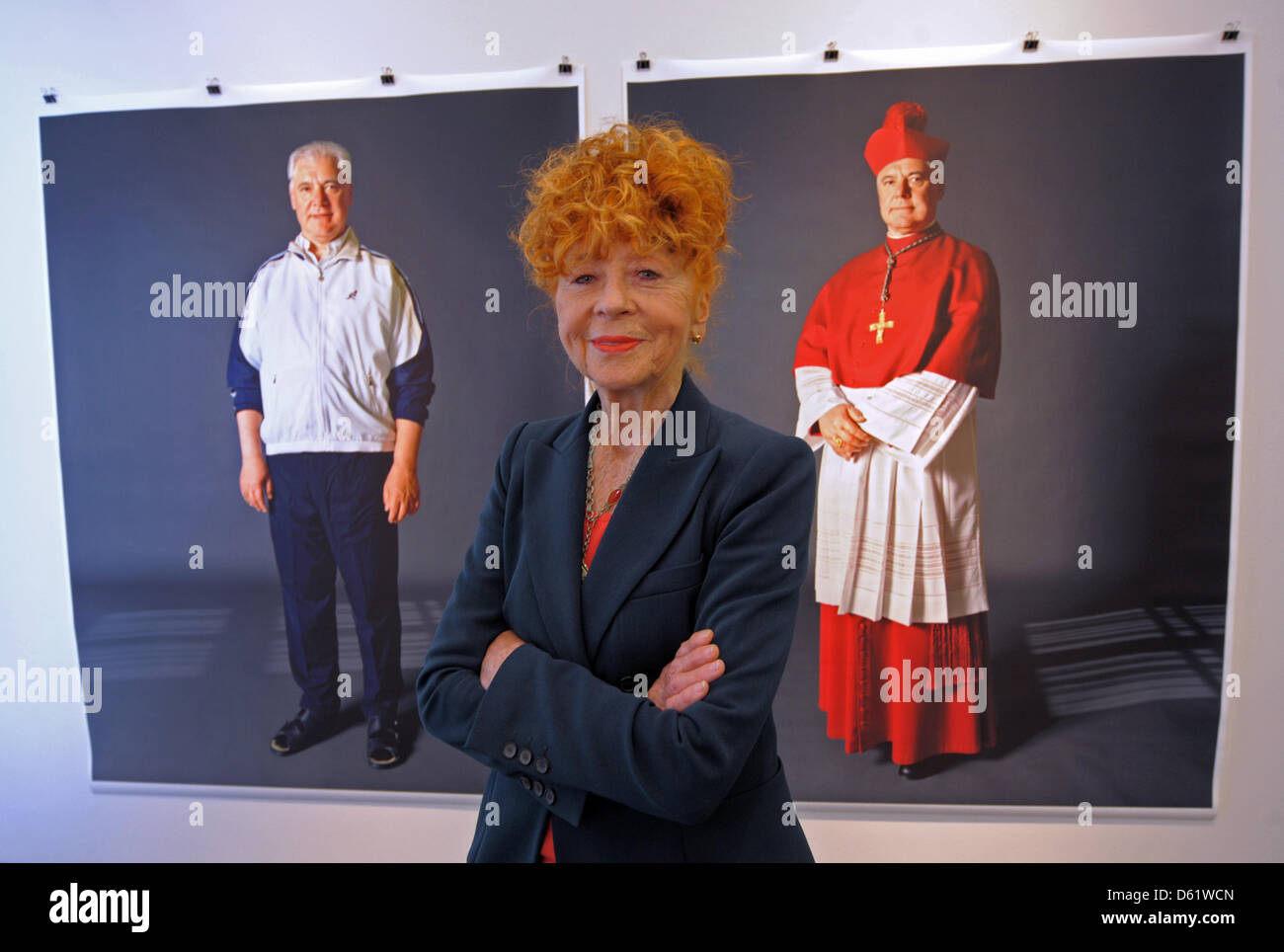 Photographer Herlinde Koelbl poses in front of two photos of Bishop Gerhard Ludwig Mueller at her new exhibition 'Kleider machen Leute' ('Clothes make the man') in Dresden, Germany, 03 May 2012. Koelbl's exhibition at the German Hygiene Museum Dresden showing people in casual and professional clothing is open until 29 July 2012.  Photo: MATTHIAS HIEKEL Stock Photo