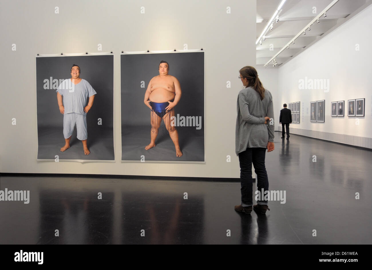 A woman vies photos of a Japanese sumo wrestler during the new exhibition 'Kleider machen Leute' ('Clothes make the man') of photographer Herlinde Koelbl in Dresden, Germany, 03 May 2012. Koelbl's exhibition at the German Hygiene Museum Dresden showing people in casual and professional clothing is open until 29 July 2012.  Photo: MATTHIAS HIEKEL Stock Photo