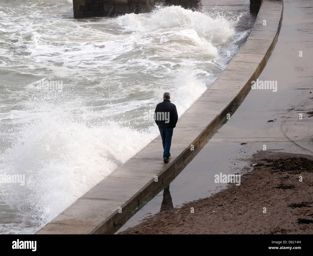Man in danger of getting wet walking on the sea wall at Scarborough South Beach (there is no alternative route). Stock Photo