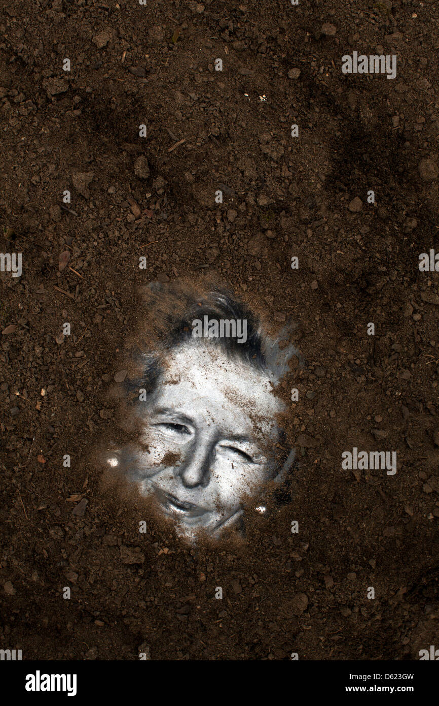 Tramp the dirt down. A picture of former British Prime Minister Margaret Thatcher is buried in soil Stock Photo