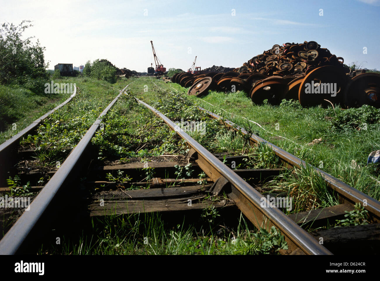 Woodhams of Barry Island train scrapyard in Wales in 1980 with overgrown railway line and scrap wheels in background Stock Photo