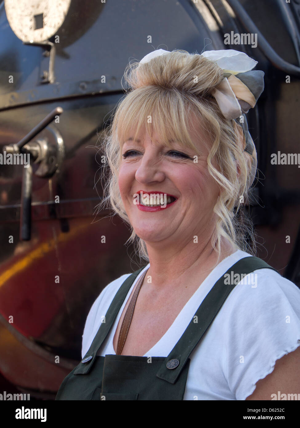 Woman smiling  dressed in  costume for 40s weekend on Sheringham station in Norfolk East Anglia England Stock Photo