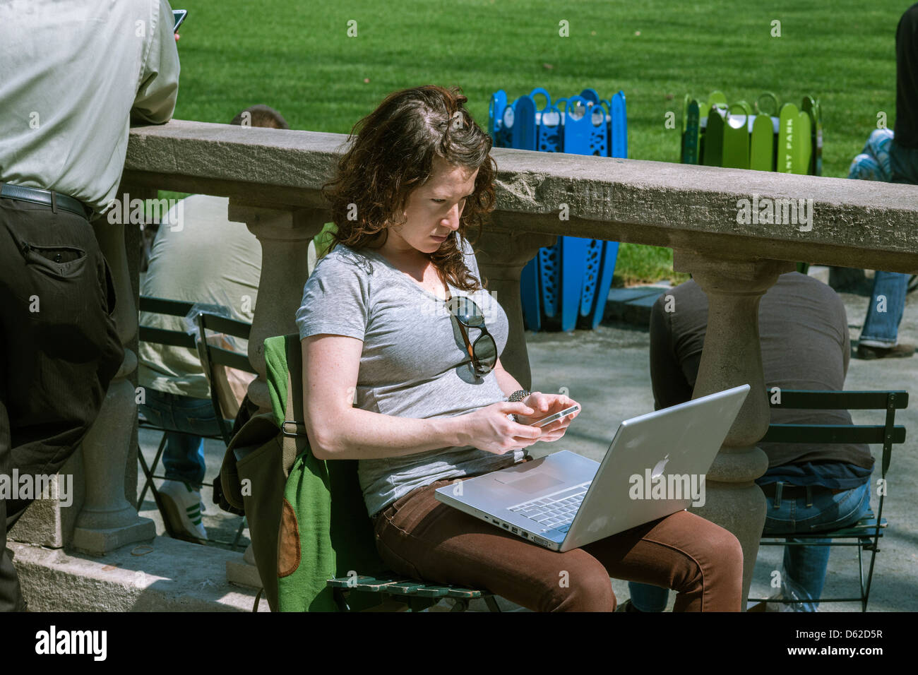 A park visitor with her laptop computer and cell phone in Bryant Park in New York Stock Photo