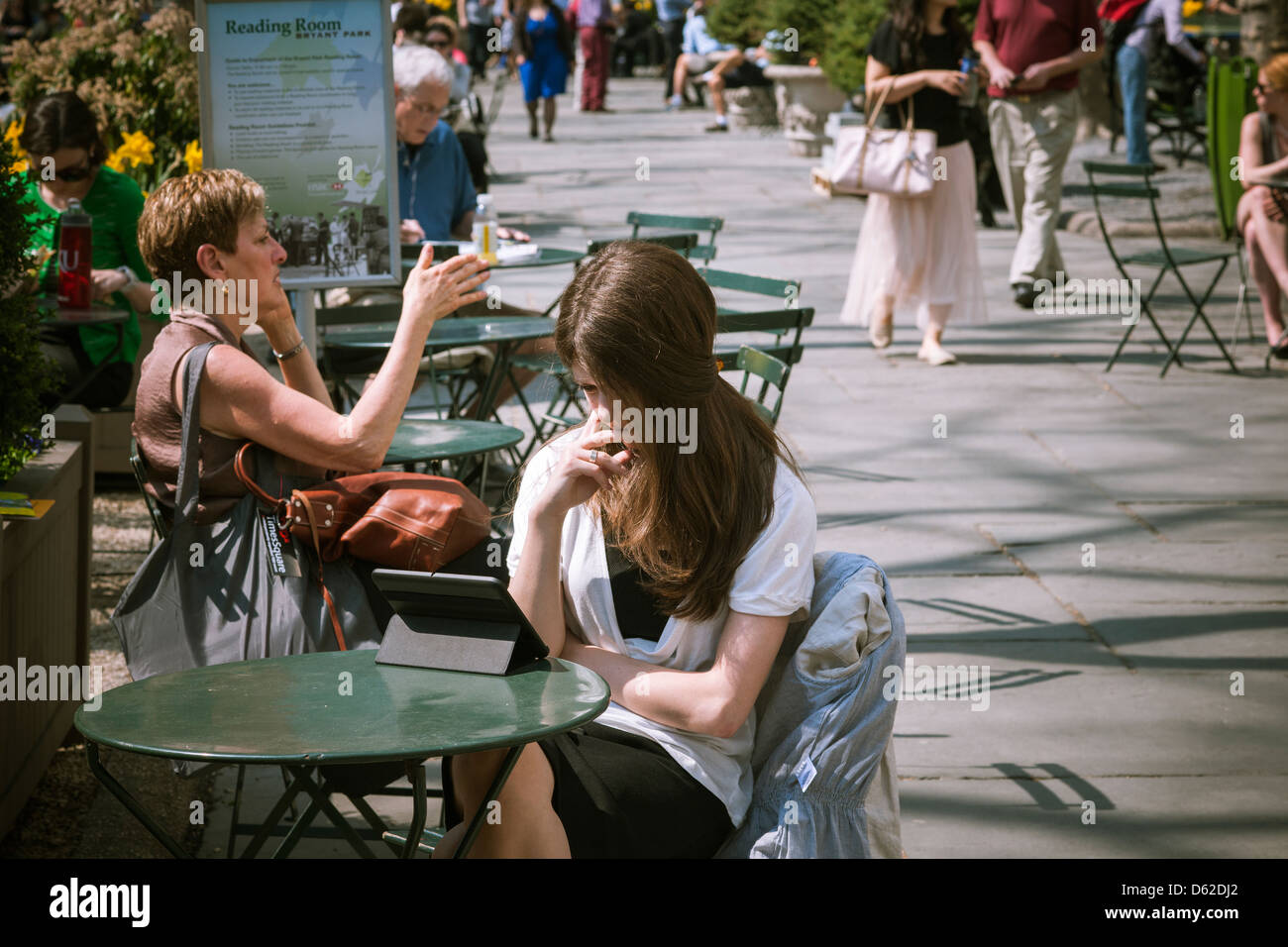 A park visitor with her tablet computer in Bryant Park in New York Stock Photo