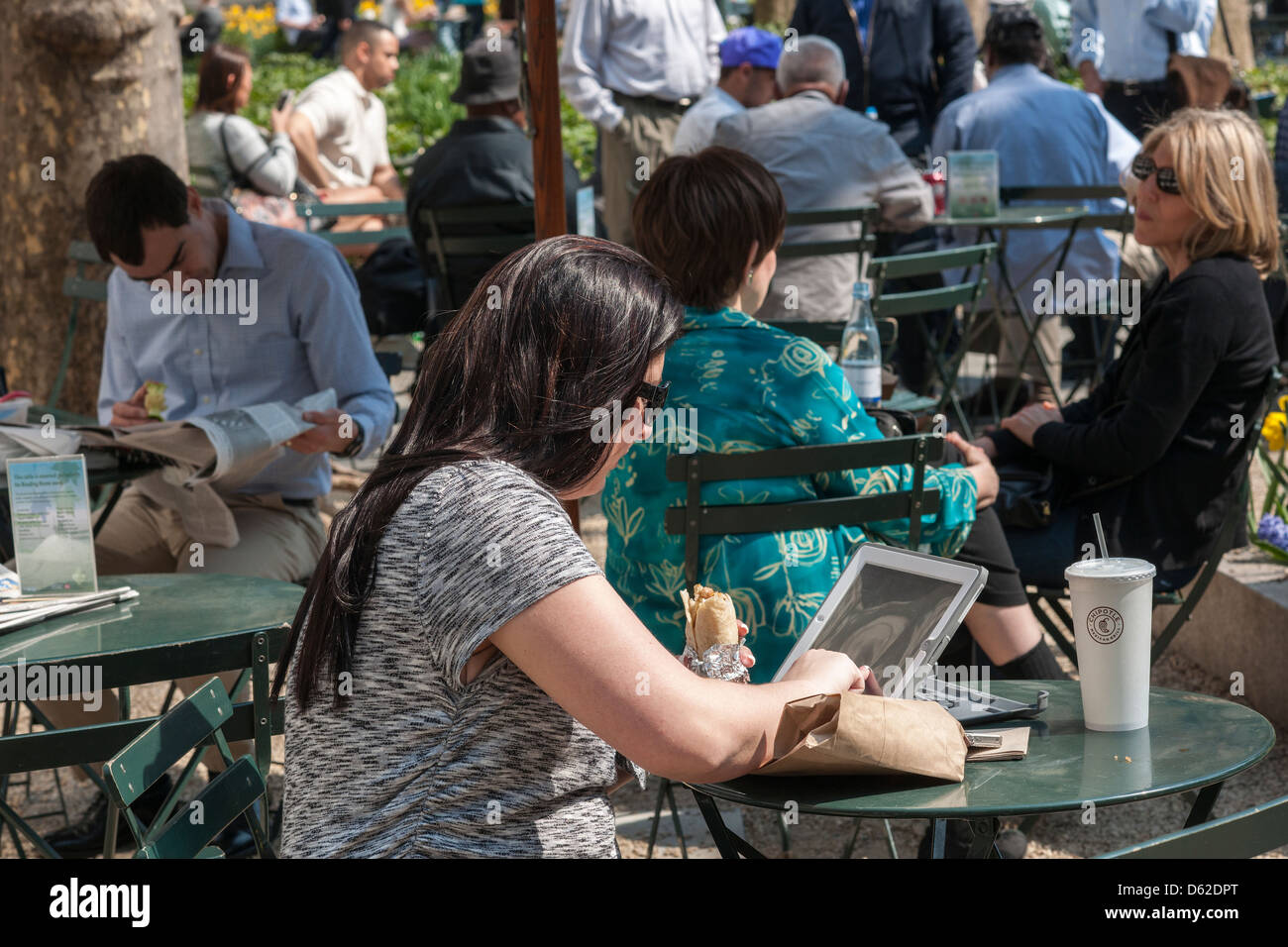 A park visitor with her tablet computer in Bryant Park in New York Stock Photo