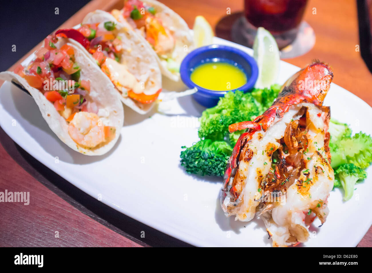 Close up of seafood dish - grilled lobster tail with shrimp tacos, butter and broccoli Stock Photo