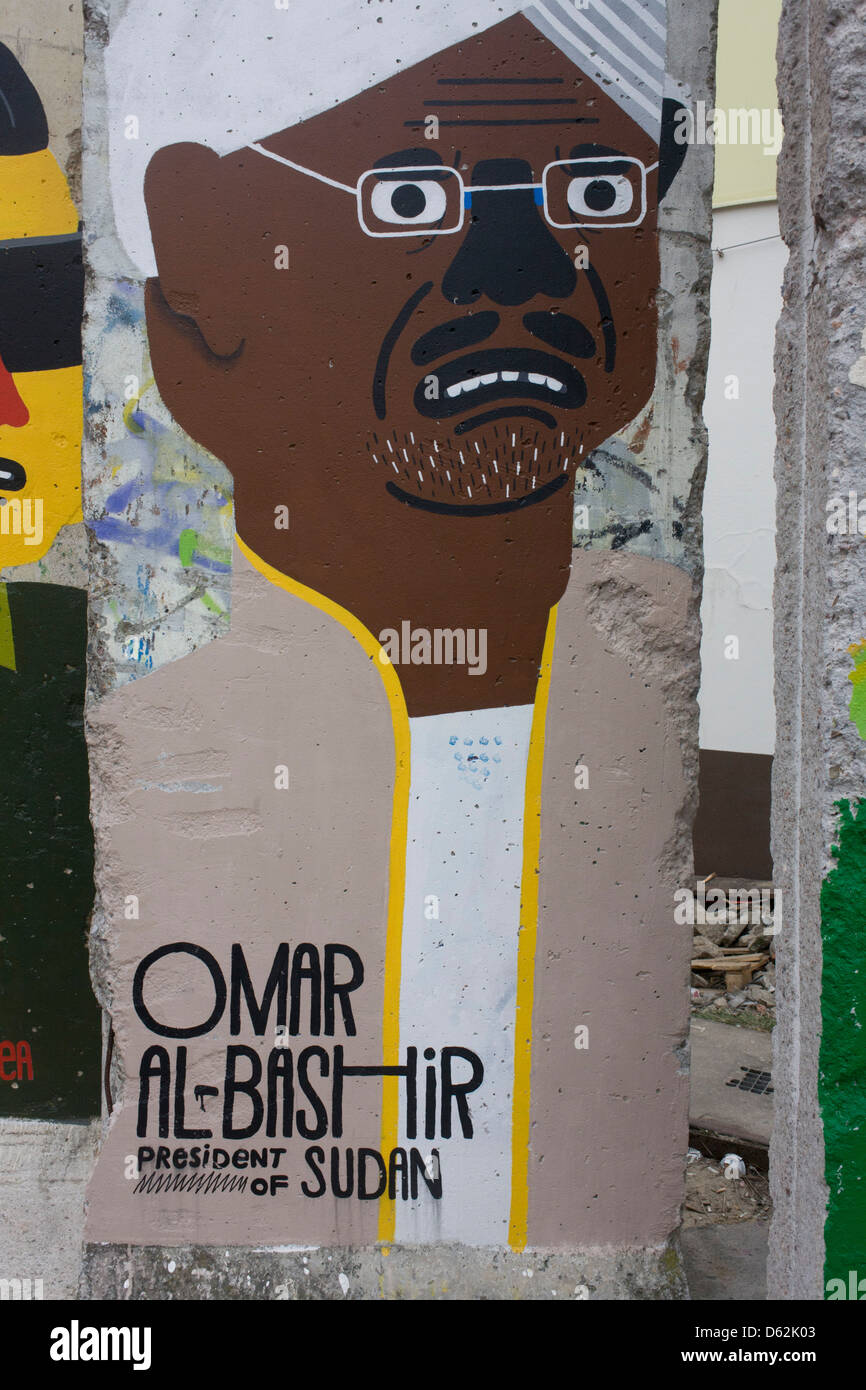 An image of Omar al-Bashir, President of Sudan, adorns an old section of the old Berlin Wall opposite the former Checkpoint Charlie, the former border between Communist East and West Berlin during the Cold War. The Berlin Wall was a barrier constructed by the German Democratic Republic (GDR, East Germany) starting on 13 August 1961, that completely cut off (by land) West Berlin from surrounding East Germany and from East Berlin. .. (More in Description). Stock Photo