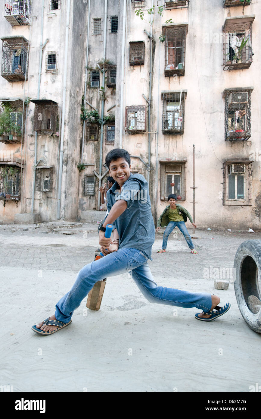 A boy plays cricket by an apartment block in Mumbai, Maharastra, India Stock Photo
