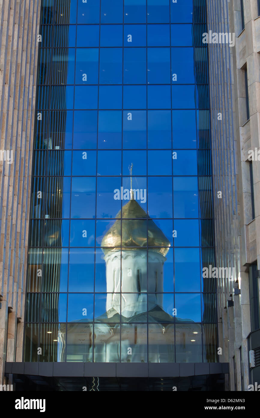 Old orthodox church reflected in a glass wall of new office building in the downtown of Moscow Stock Photo