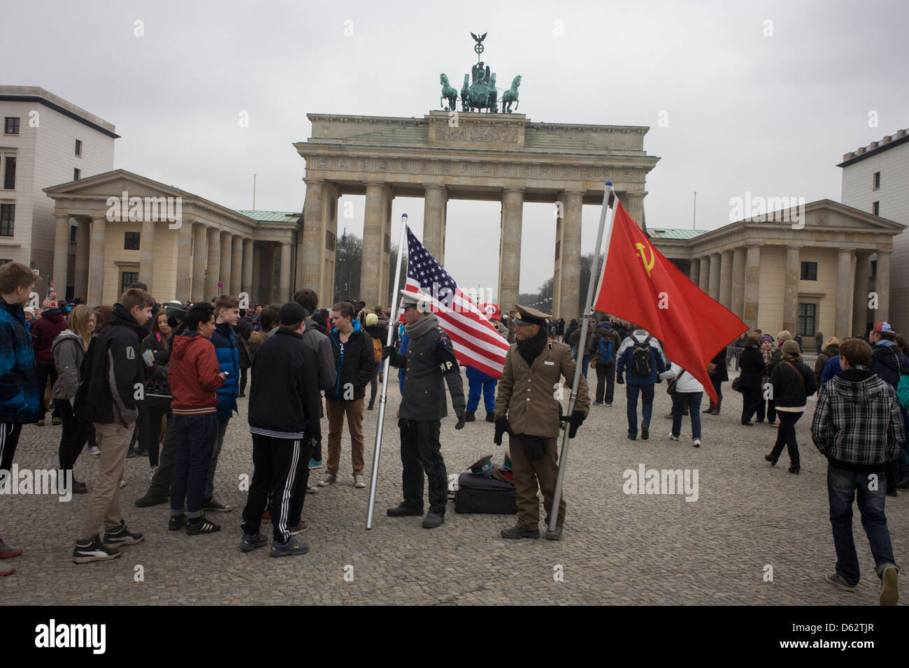Actors in US and Soviet army uniforms hold flags to recount German history during the second world war and later, the cold war - beneath the Brandenburg Gate in Unter den Linden in central Berlin, Germany. Stock Photo