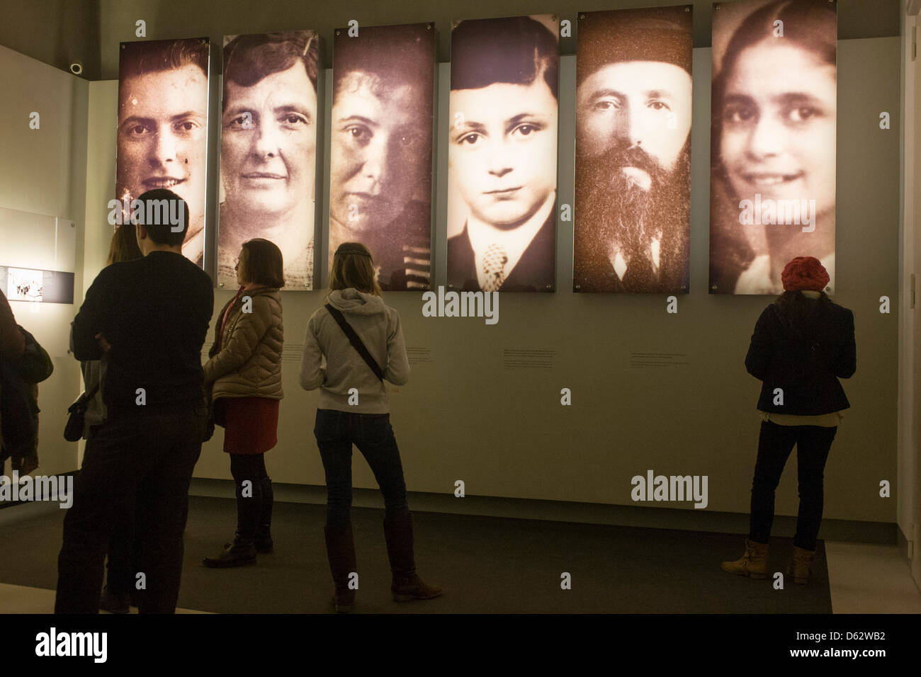 Visitors standing beneath panels with the faces of Jewish victims of the Holocaust, read the stories and history of Nazi anti-Semitism, in central Berlin, Germany. Stock Photo