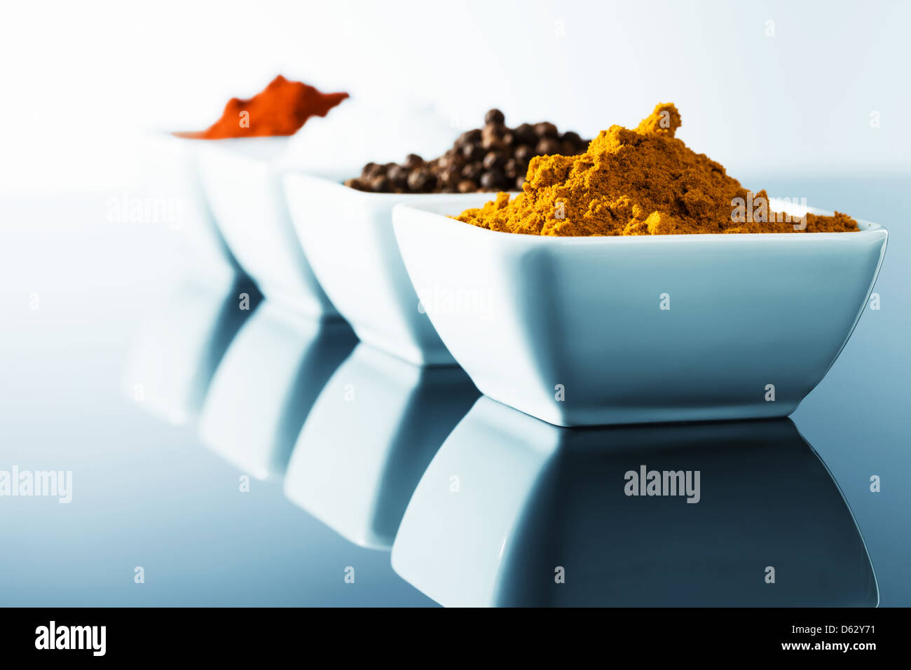 spices in small bowls in row with blue light Stock Photo Alamy