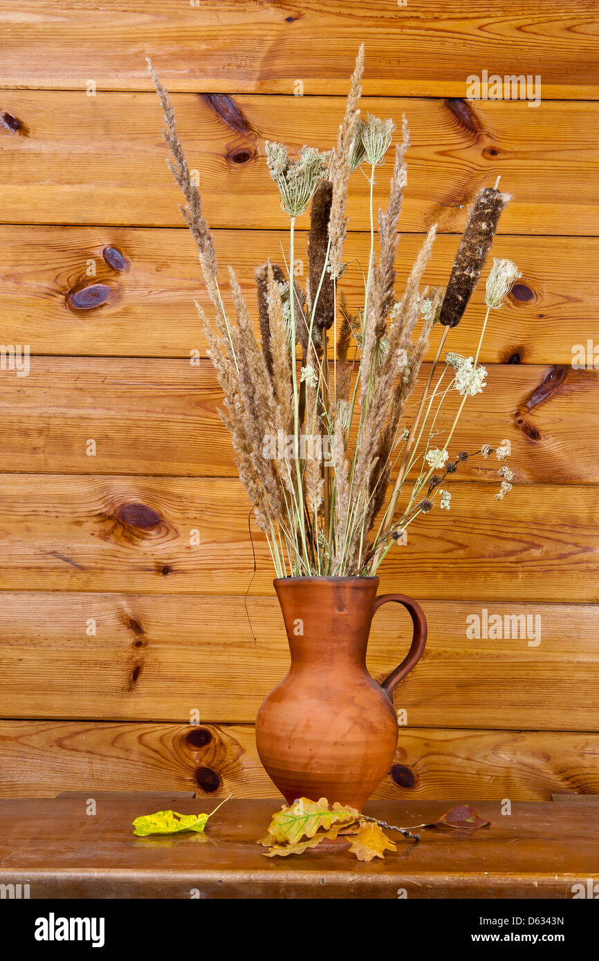 Clay jug with dry stalks of a reed on a brown wooden background Stock ...