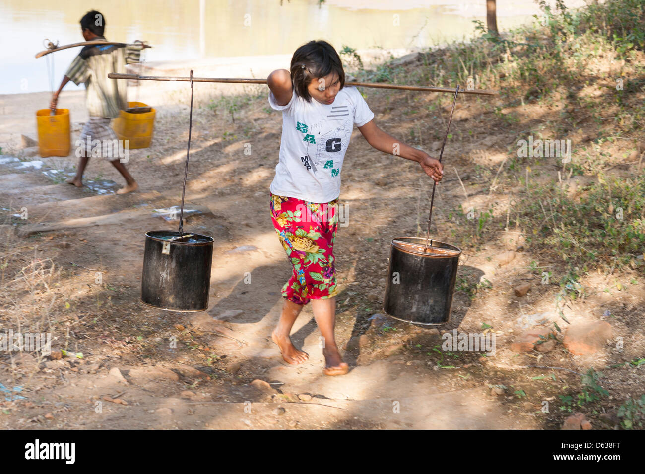 Young girl carrying a pannier filled with water, Minnanthu, Bagan, Myanmar, (Burma) Stock Photo