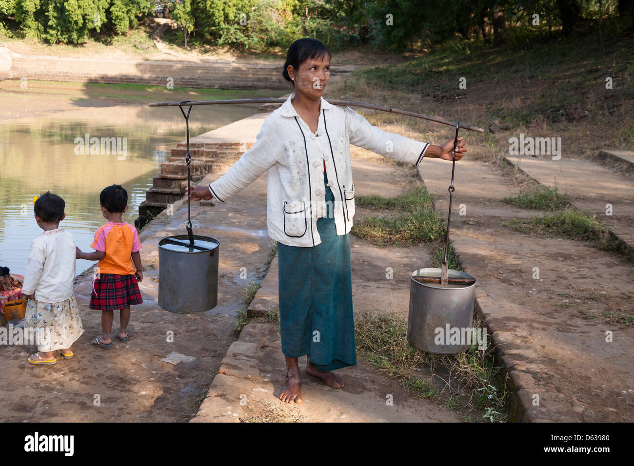 Woman carrying a pannier filled with water, Minnanthu, Bagan, Myanmar, (Burma) Stock Photo