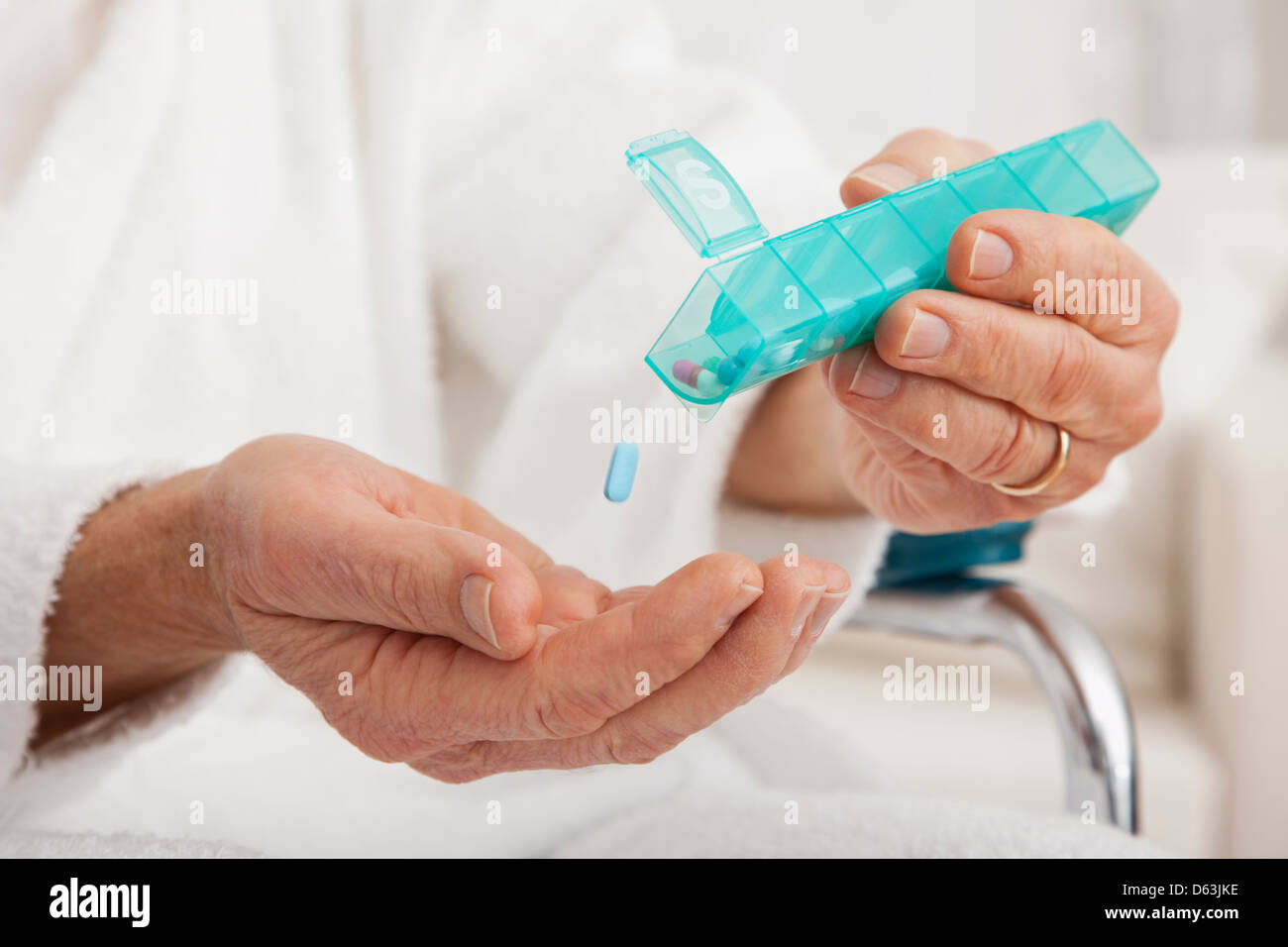 Close up of senior's hands taking pill from pill organizer Stock Photo