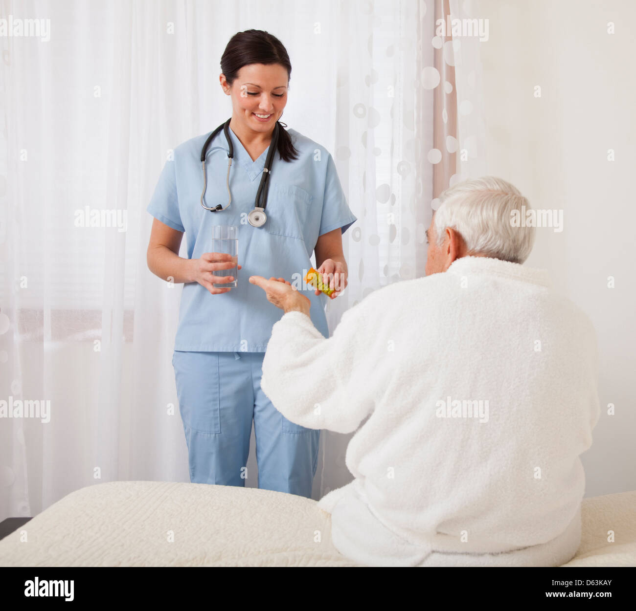 Nurse giving medicine to senior patient Stock Photo