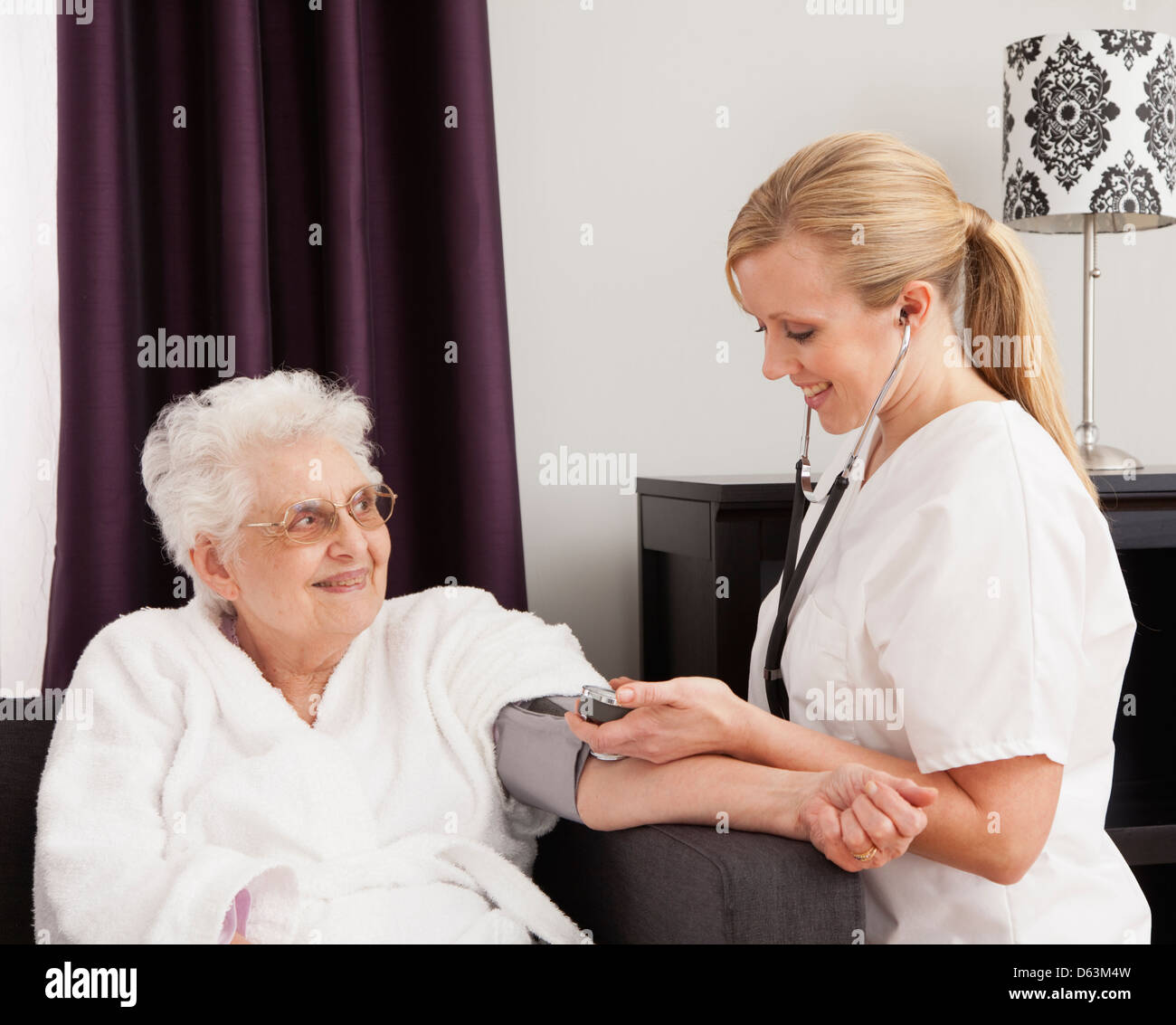 Nurse measuring blood pressure of a senior woman Stock Photo