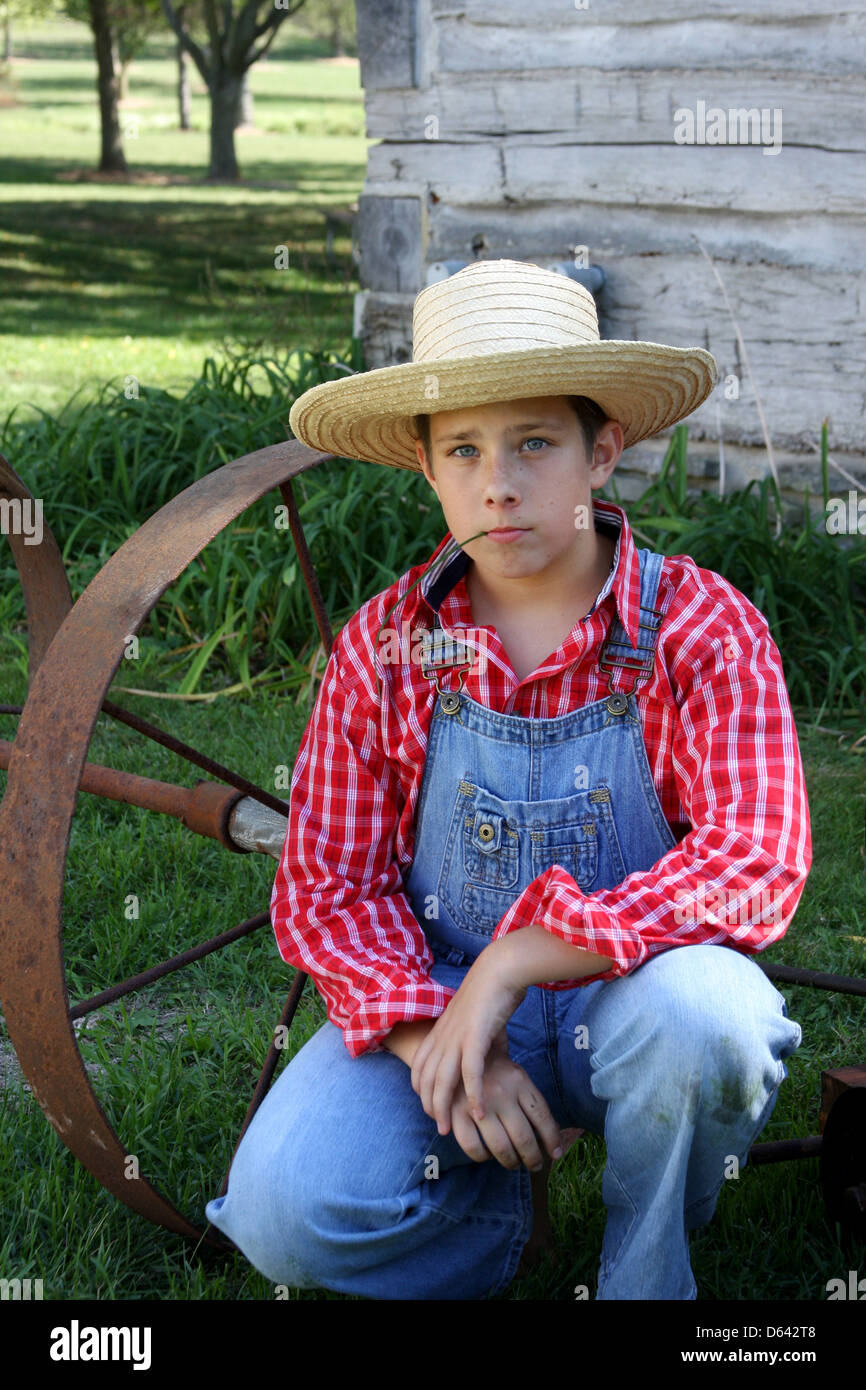 A young farmer boy next to antique farm equipment Stock Photo - Alamy