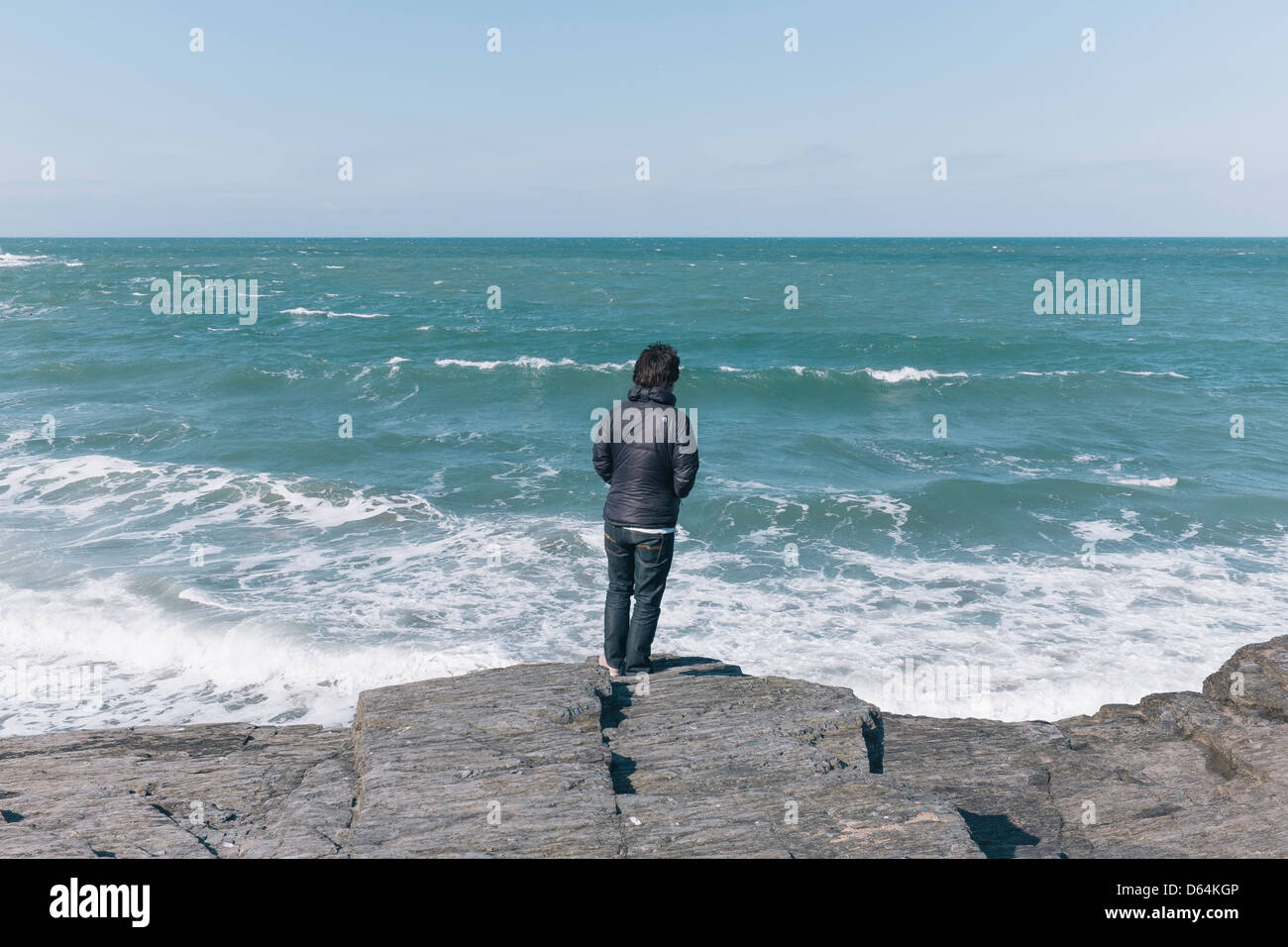 Man on rocks looking out to sea Stock Photo - Alamy