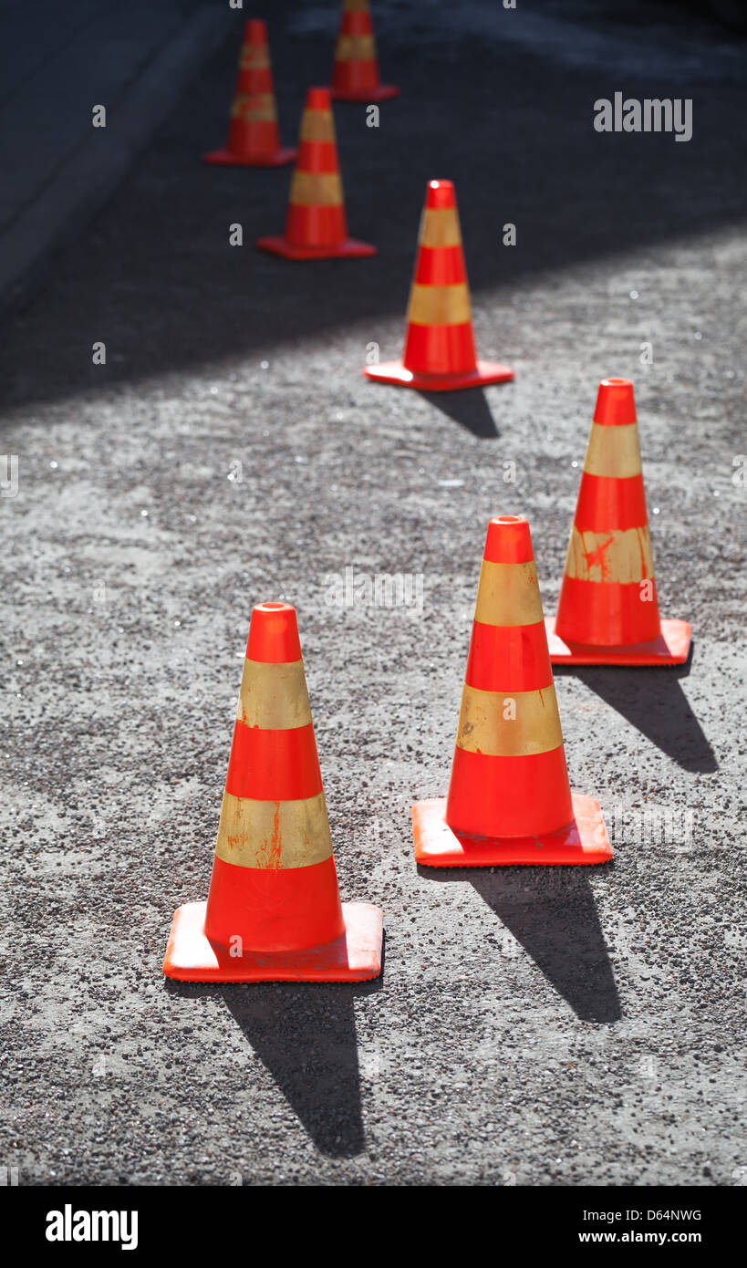 Red and yellow striped warning cones in line on asphalt road Stock Photo