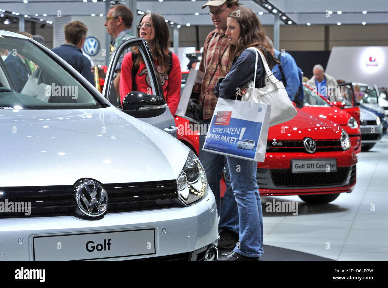 Visitors stroll around exhibited cars and motor vehicles of car manufacturer Volkswagen (VW) at the automobile fair AMI in Leipzig, Germany, 2 June 2012. German and international car manufacturers present their latest car novelties at the Leipzig trade fair centre from 2 June to 10 June 2012. Around 280,000 visitors are expected to attend the fair which features up to 450 exhibitor Stock Photo