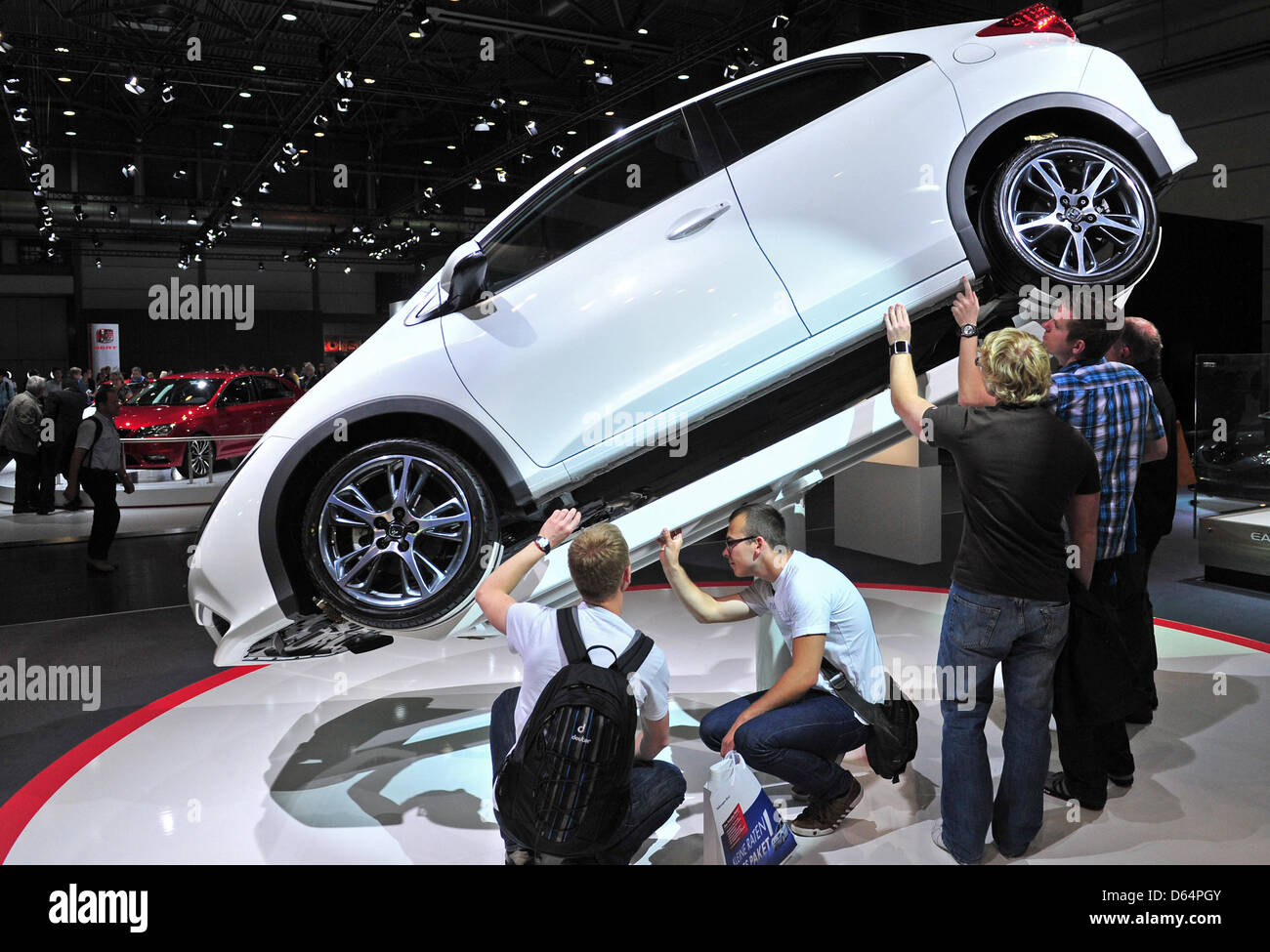 Visitors stroll around exhibited cars and motor vehicles of car manufacturer Honda, featuring also the Honda Civic, at the automobile fair AMI in Leipzig, Germany, 2 June 2012. German and international car manufacturers present their latest car novelties at the Leipzig trade fair centre from 2 June to 10 June 2012. Around 280,000 visitors are expeocted to attend the fair which feat Stock Photo