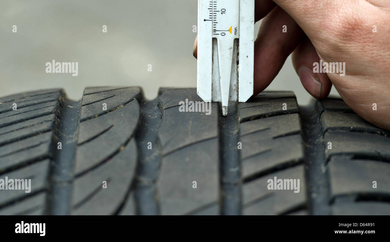 A man measures the pattern depth of a summer tire with a vernier ...
