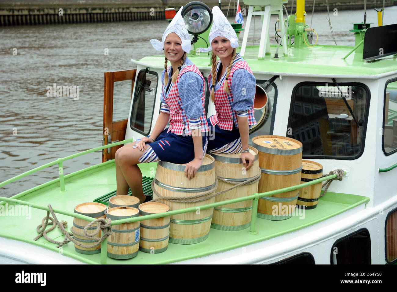 Two Dutch girls Michelle (L) and Shanna sit on barrels containing the first new Matjes (young herring) of the season in Bremen, Germany, 06 June 2012. The shipment arrives in Bremen directly from the Netherlands. The start of the Matjes season will be celebrated in Bremen. Photo: INGO WAGNER Stock Photo