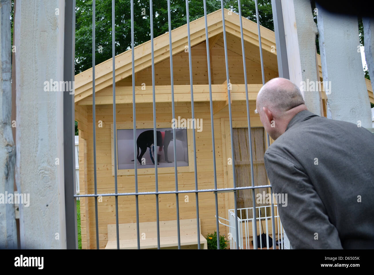 A man stands in front of the artists' hut of Thai artist  Araya Rasdjarmrearnsook at the documenta art exhibiton in Kassel, Germany, 07 June 2012. Screens showing videos of dogs are fixed to the surrounding fence of the hut. The documenta (13) art exhibition opens to the public on 09 June and runs until 16 September. Photo: UWE ZUCCHI Stock Photo