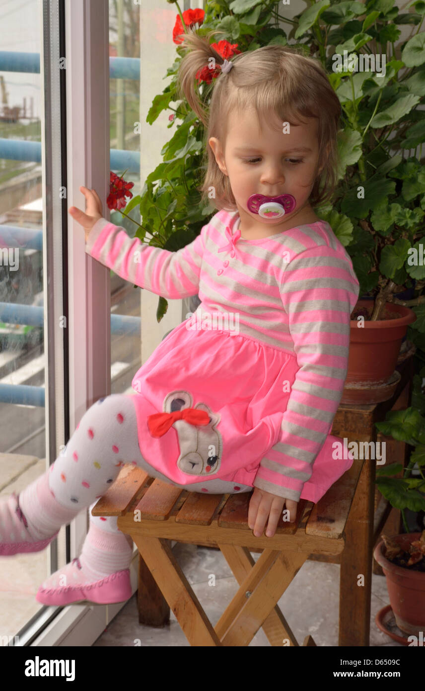 Little girl in pink dress sitting on a chair at balkony Stock Photo - Alamy