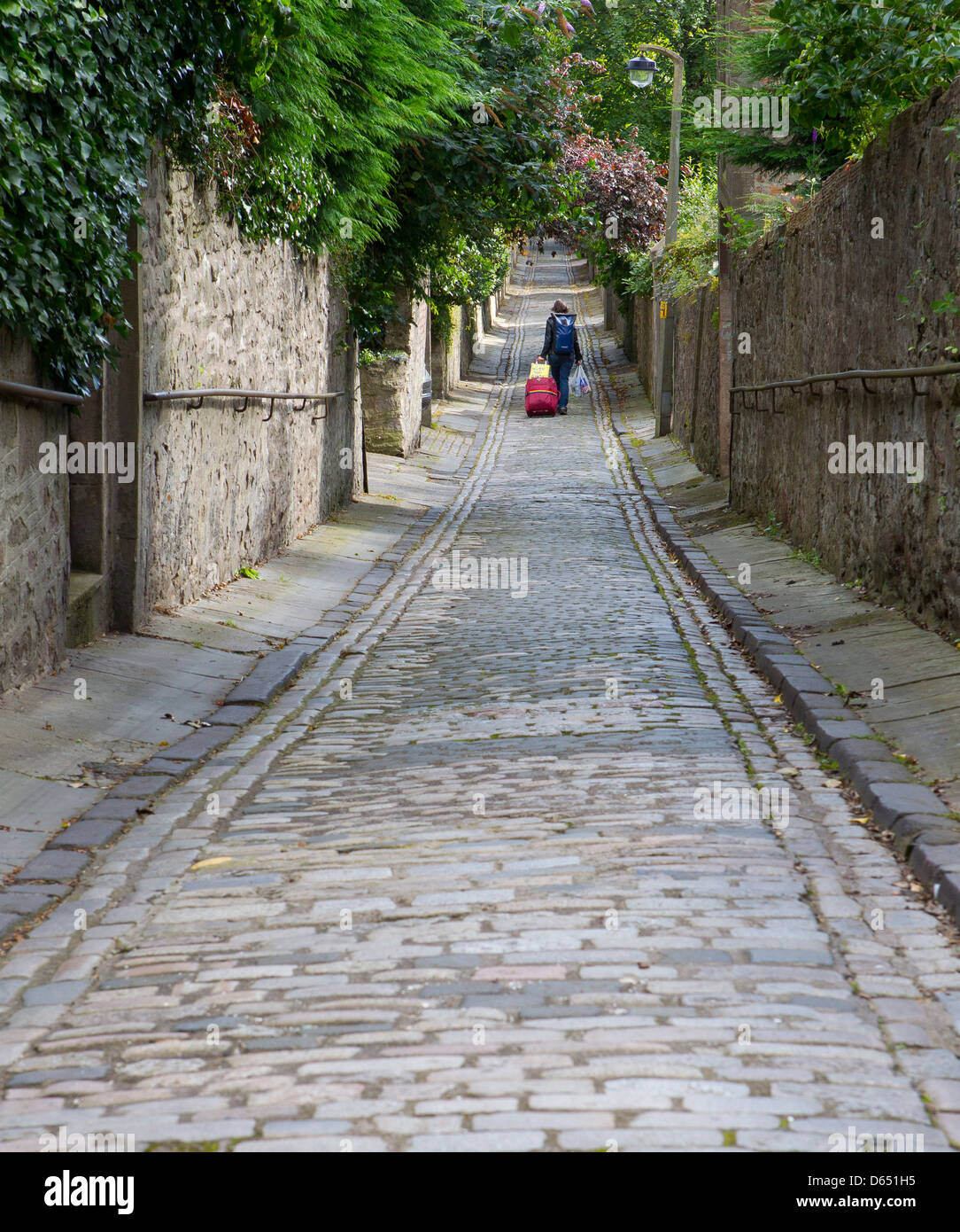 person walking down straight cobbled lane Stock Photo