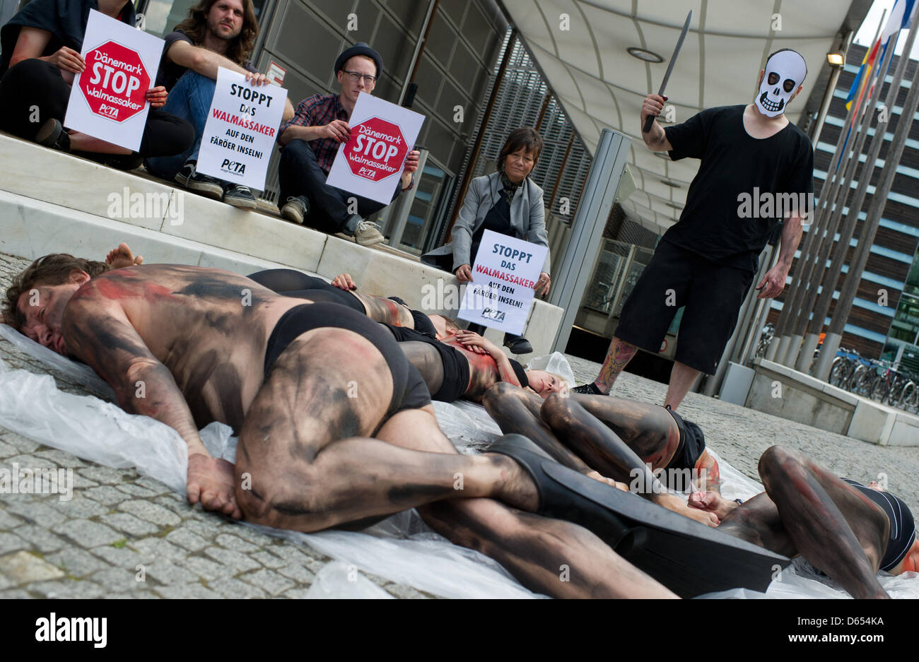 Peta activists symbolically dressed as long-finned pilot whales lie in front of the Danish embassy during a protest action against the hunting of long-finned pilot whales in Berlin, Germany, 11 June 2012. The protestors demonstrate against the whale hunting tradition at the Faroes islands killing hundreds of long-finned pilot whales every year. Photo: TIM BRAKEMEIER Stock Photo