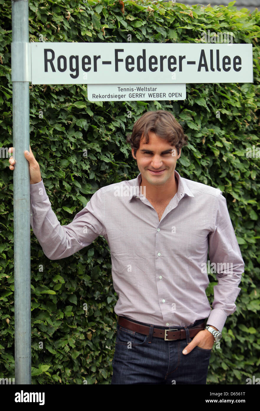 Swiss tennis professional Roger Federer poses next to a street sign ...