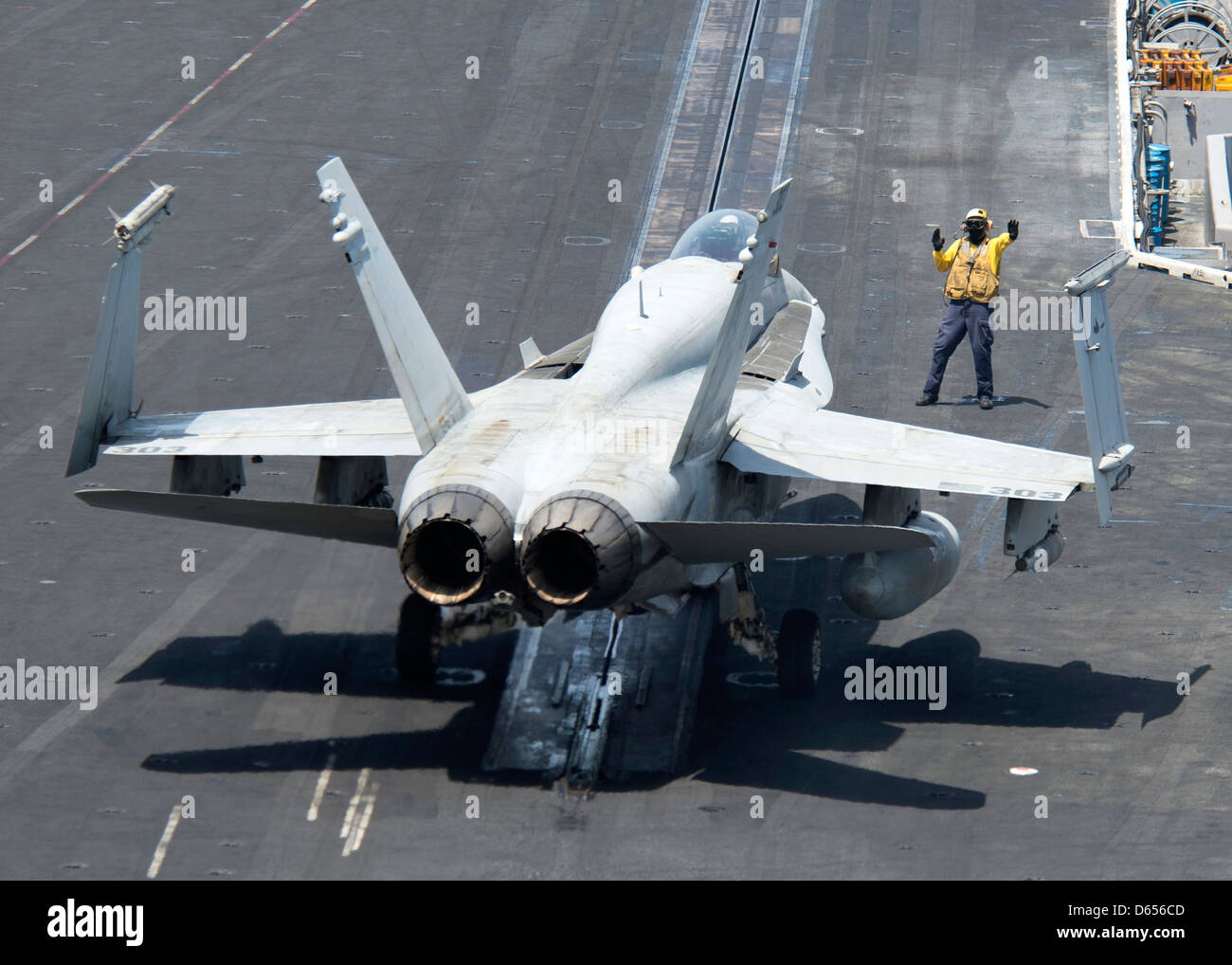 A US Navy plane director guides an F/A-18C Hornet onto a catapult for take off on the flight deck of aircraft carrier USS Dwight D. Eisenhower April 9, 201 in the North Arabian Sea. Stock Photo