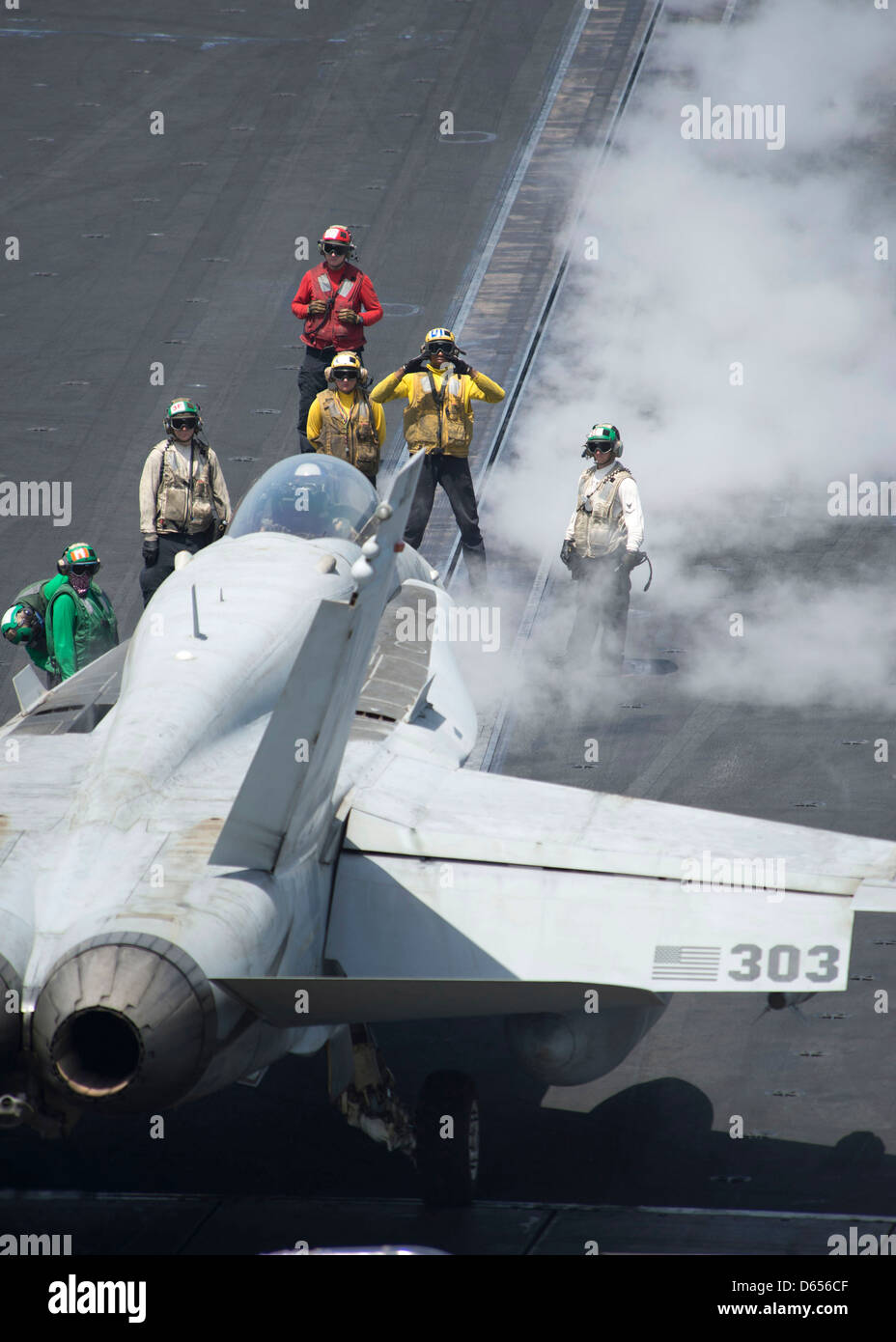 A US Navy plane director guides an F/A-18C Hornet onto a catapult for take off on the flight deck of aircraft carrier USS Dwight D. Eisenhower April 9, 201 in the North Arabian Sea. Stock Photo