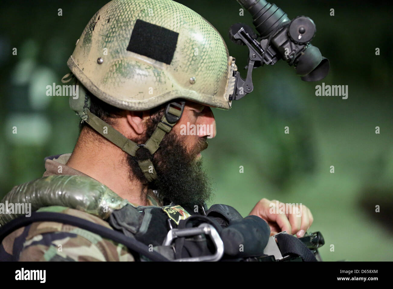 An Afghan National Army commando with the 1st Special Operations Kandak adjusts the laser on his weapon during night vision training April 8, 2013 in Behsud district, Nangarhar province, Afghanistan. Stock Photo