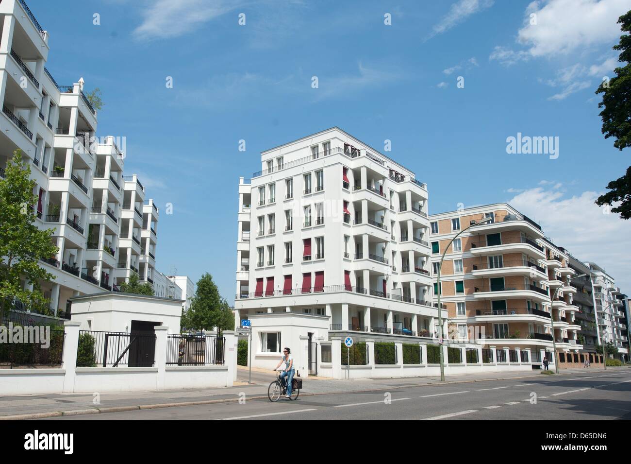 View of A woman on her bicycle passes by a luxury apartment house at Volkspark ...